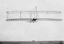 1902 glider soars above sand dunes